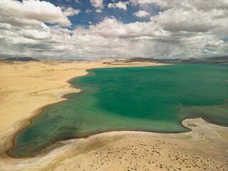 Emerald lake in the sands, view from the top. A lake in Mongolia during the golden hour. The beach overlooks a beautiful lake. View of the lake from a height.