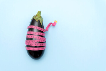 Fresh Eggplant wrapped with pink measuring tape on blue background