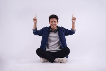 Portrait of young Asian man sitting and posing on a white background