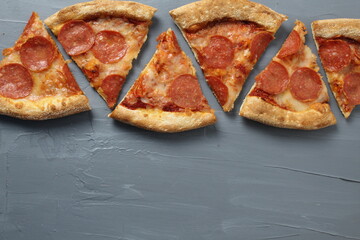 Edging of slices of pizza on a gray background with space for copyspace text. View from above. Pizza background for a cafe, pizzeria