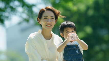 Obraz premium 3歳の息子に水を飲ませる母親