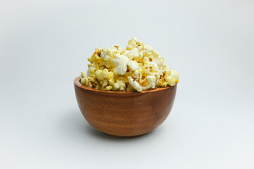 Fresh popcorn in a white wooden bowl isolated on a white background. Suitable for design purposes, advertisements, recipe blogs, and cinema promotions