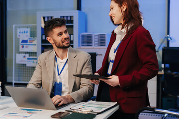 Financial analysts work overtime analyzing data on tablets, laptops, and graphs. Collaboration,...