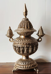 Intricate Indian antique metal pot with ornate design displayed on a wooden surface
