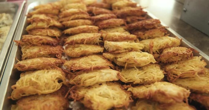 A tray of golden, crispy potato pancakes neatly arranged on a buffet table in a hotel. Represents comfort food, hospitality, and delicious meal options during travel