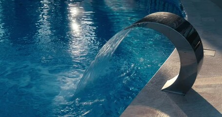 A sleek hydromassage fountain pours a stream of water into a sparkling pool, highlighting relaxation, modern spa design, and the rejuvenating benefits of water therapy in a serene setting