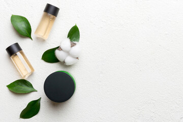 Organic cosmetic products with cotton flower and green leaves on cement background. Copy space, flat lay