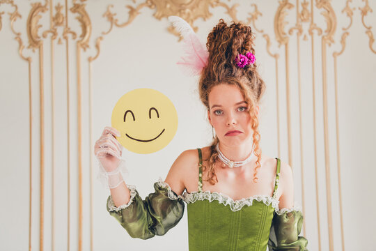 Young woman in baroque attire contrasting modern emotions holding a cheerful face icon