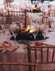 Beautiful table decoration for luxury  event in pink and gold, cutlery and tableware, banquet hall arrangement decor, celebration in restaurant with flowers, candles on a wedding reception party