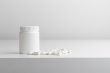 White pills and plastic medicine bottle on a white background with copy space. Medicine and health concepts include a jar with pills or vitamins. High-quality photo mock-up banner