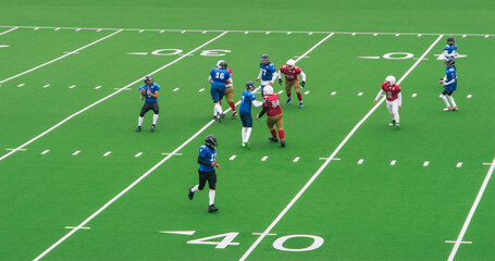 American Football Players Sprinting to Make a Goal. Authentic Gridiron Game on a Big Green Outdoors Field with Markings. Opposing Teams Playing a Championship Tournament Match