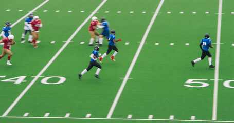 American Football Clash Unfolds as Professional Male Athletes in Red and Blue Jerseys Tackle Competition on a Green Outdoors Field. Agile Footballers Scoring Points