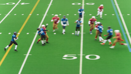 American Football Clash Unfolds as Professional Male Athletes Tackle Competition on a Green Outdoors Field. Agile Blue Footballers Running Away From Competition