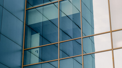 mirrored windows of the facade of an office building with blue panels and yellow window frames with a distorted reflection of the house