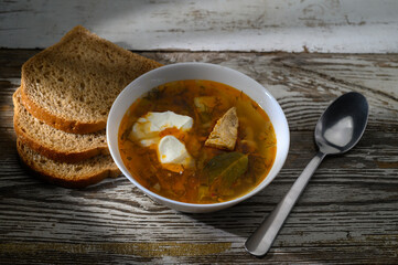 Hearty bowl of traditional soup served with artisanal bread on rustic wooden table