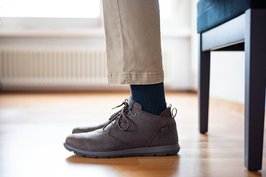Unrecognizable man's legs in causal pants and brown leather shoes. Sitting on chair pose, interior waiting room shot, natural light, ground level close up view