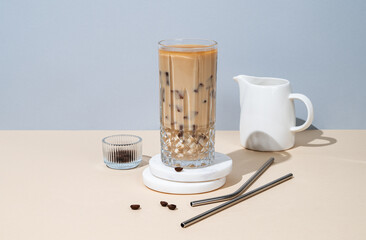 Iced coffee latte in a tall glass with milk on a yellow and blue background