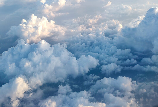 Soft Fluffy Clouds at High Altitude Captured During Flight in Golden Hour Light