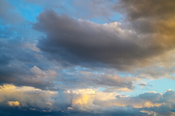 Shifting clouds dance across the vibrant sky at sunset, painting the horizon with golden hues