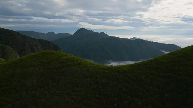 Eramon mountain at Chalatenango, El Salvador surrounded by a sea of clouds as aerial drone camera performs a fly by of the narrow trail leading to the summit and looking down