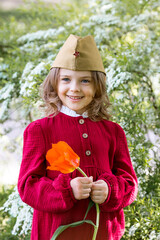 The concept of the May 9th holiday. Portrait of a beautiful girl in a military cap with a tulip...