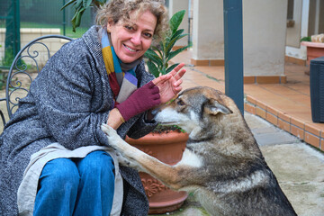 Smiling woman petting czechoslovakian wolfdog in garden