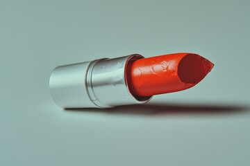 broken lipstick bullet rests on its side showcasing its bold red hue and creamy texture. pristine white background highlights rich pigment and details of broken surface.