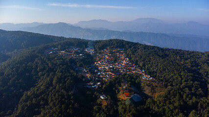 Aerial view of rural village, fertile agricultural land and mountain ranges in the background in northern Thailand.