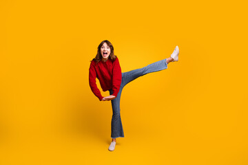 Obraz premium Happy young woman posing energetically in a bright red sweater against a vibrant yellow background