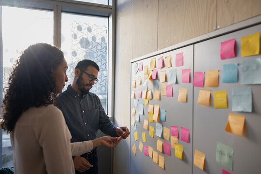 Colleagues using sticky notes to brainstorm ideas in an office