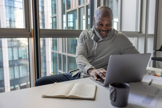 Mature African American businessman with headphones on a video call in an office