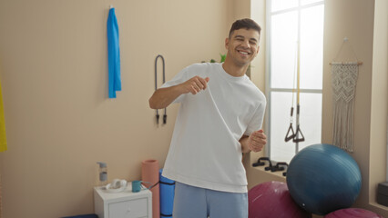 Young man smiling in gym environment with exercise equipment and bright interior showcasing active...