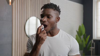 African American ethnic man applying fresh breath spray prevent stink morning hygiene of mouth...