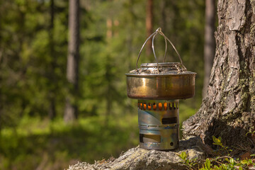 Making coffee on a cambing alcohol burner in the forest on a sunny day