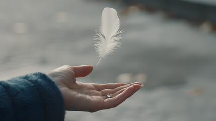 close-up of two hands, one holding the other's fingers with an outstretched hand and palm facing upwards, gently blowing away a small white feather floating in mid-air