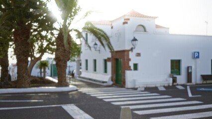 Blurry street scene in lanzarote, spain with white buildings, palm trees, and defocused background representing typical canary islands architecture and atmosphere.