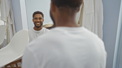 Obraz premium Handsome young man smiling while looking at his reflection in a spa's indoor wellness room