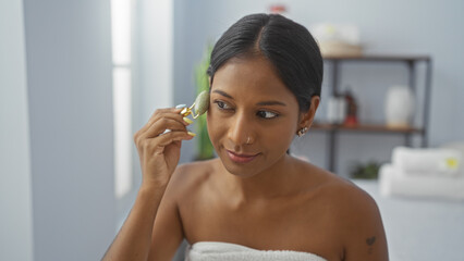 Beautiful hispanic woman at a spa performs a skincare routine in a serene wellness room