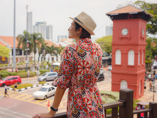 Fototapeta premium Young woman in ethnic dress and hat exploring the vibrant streets of Malacca, Malaysia. A blend of cultural heritage, colorful architecture, and tropical charm. Perfect travel and lifestyle moments.