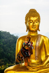 Obraz premium Statue de Bouddha doré avec des bracelets sur fond de montagnes au Tiger Cave Temple, Krabi, Thaïlande