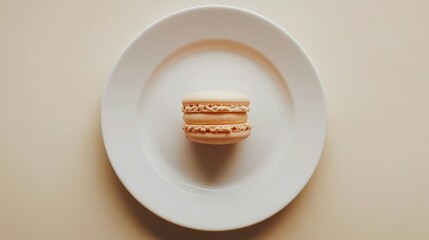 Two beige macarons are delicately stacked on a pristine white plate against a muted peach background, creating a simple yet elegant culinary scene.