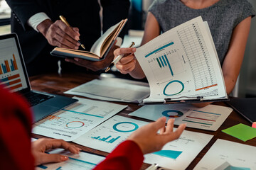 A group of financial analysts work together to discuss company financial statistics reports....