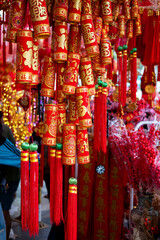 Close-up of Chinese New Year decorations: gold ingots, red lanterns, and firecrackers hang on a string. Festive symbols of wealth, luck, and celebration are ready for the Lunar New Year