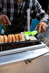 Kue Pancong being cooked on a griddle. Indonesian street food, coconut milk & rice flour cake, sprinkled with sugar. Close-up, golden brown, delicious snack. Vendor in background.  Traditional Betawi 