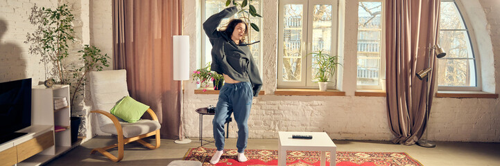 Young man in casual stylish clothes, oversized hoodie and pants, listening to music in headphone...