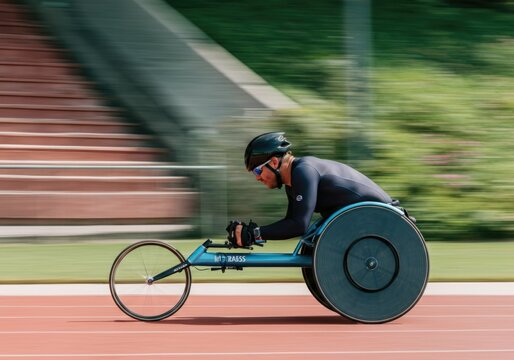 Athlete in racing wheelchair competing on outdoor track at high speed - Powered by Adobe
