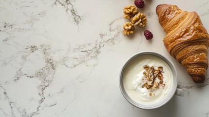 A stylish breakfast setup with a bowl of yogurt, a croissant, and a cup of coffee, placed on a marble countertop.