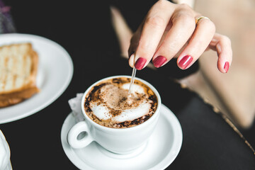 Vista superior de uma mão segurando uma xícara de café sobre uma mesa de restaurante