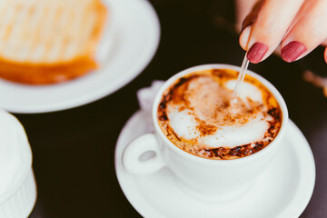 Vista superior de uma mão segurando uma xícara de café sobre uma mesa de restaurante