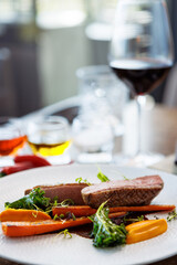 Duck fillet with sweet potato cream, roasted carrots, kale, beet-port sauce on white plate. Grilled and roasted poultry closeup served on a table for lunch in modern cuisine gourmet restaurant.